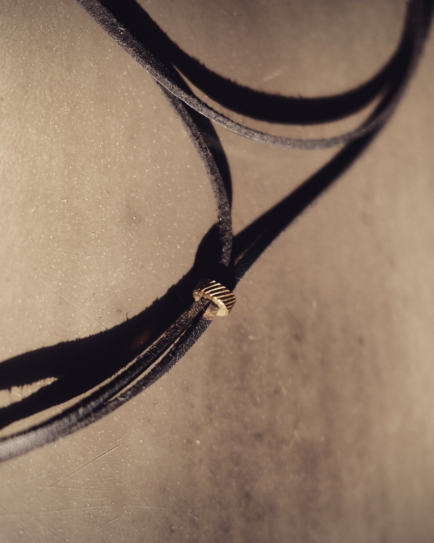 Un lien noir en cuir vegan, rehaussé de perles dorées en acier inoxydable. Audacieux, intemporel, sensuel.