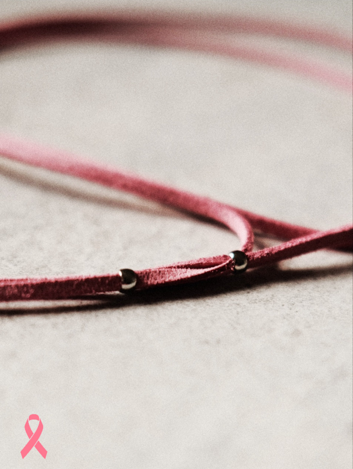 Édition limitée Octobre Rose. Un lien en suédine rose orné de perles argentées ultra fines en acier inoxydable. Féminin, solidaire, essentiel.