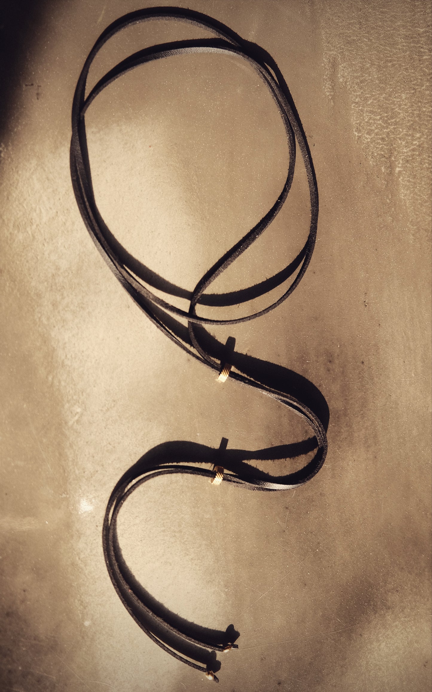 Un lien noir en cuir vegan, rehaussé de perles dorées en acier inoxydable. Audacieux, intemporel, sensuel.