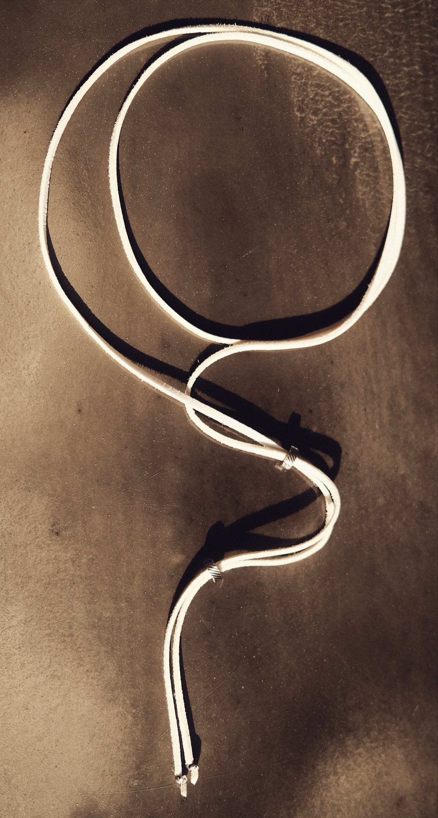 Un lien blanc éclatant en cuir vegan, ponctué de perles argentées en acier inoxydable. Pur, discret, minimal.