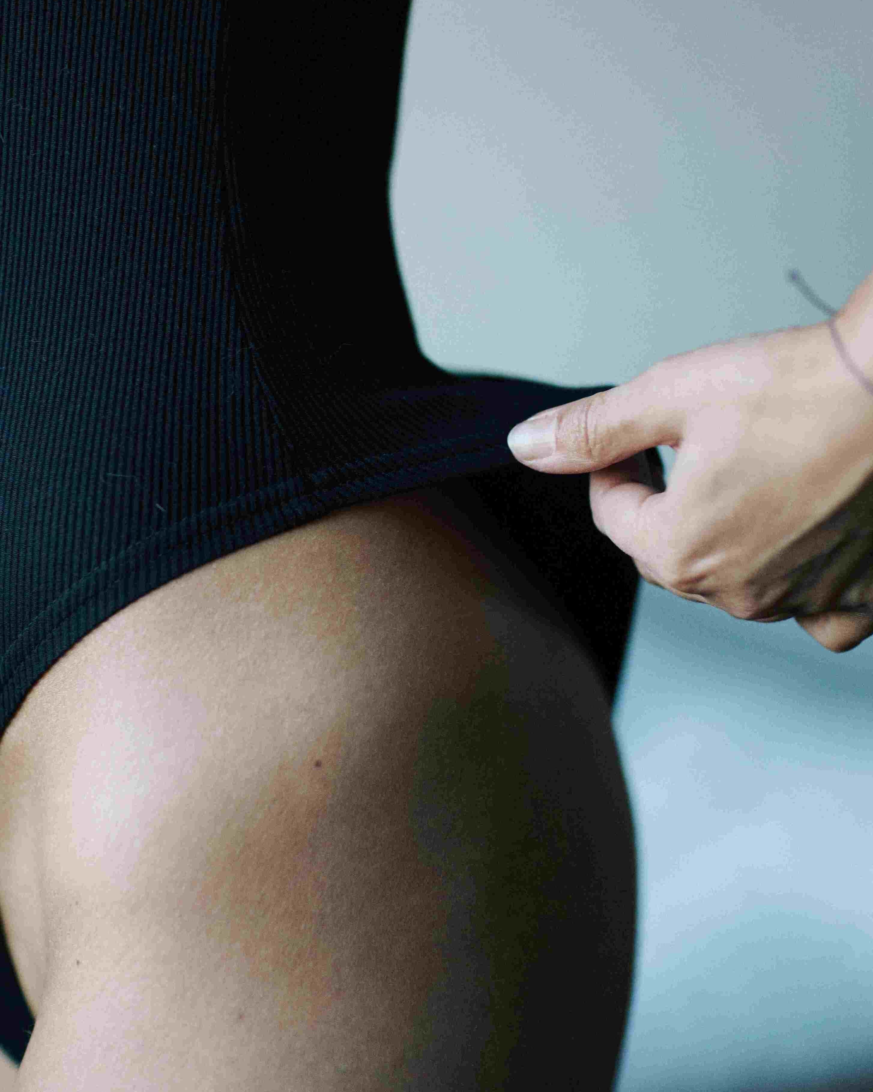 VERSATILE. Body Noir avec dos nu. Côtelé. Manches longues, encolure 2 boutons.