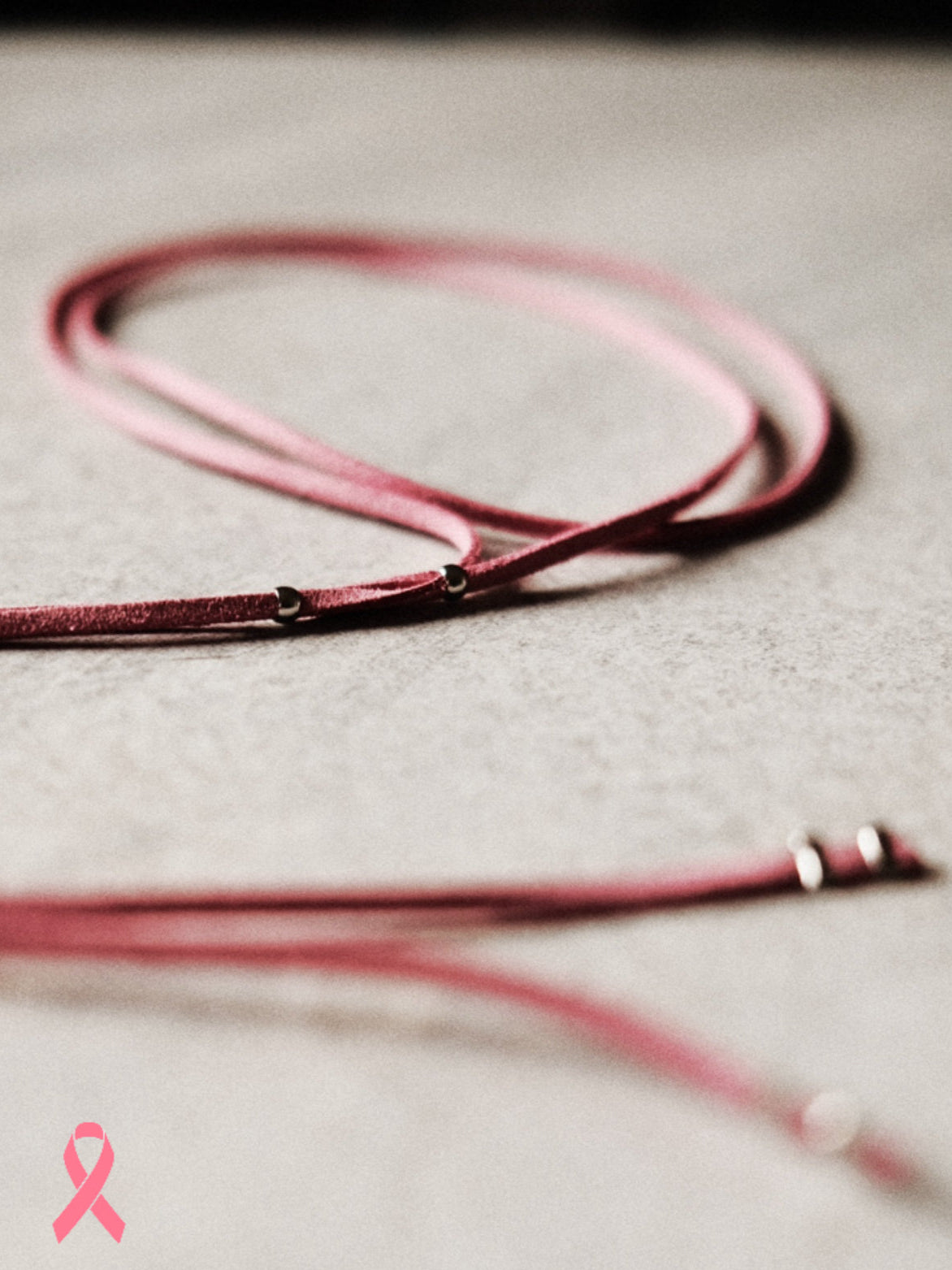 Édition limitée Octobre Rose. Un lien en suédine rose orné de perles argentées ultra fines en acier inoxydable. Féminin, solidaire, essentiel.